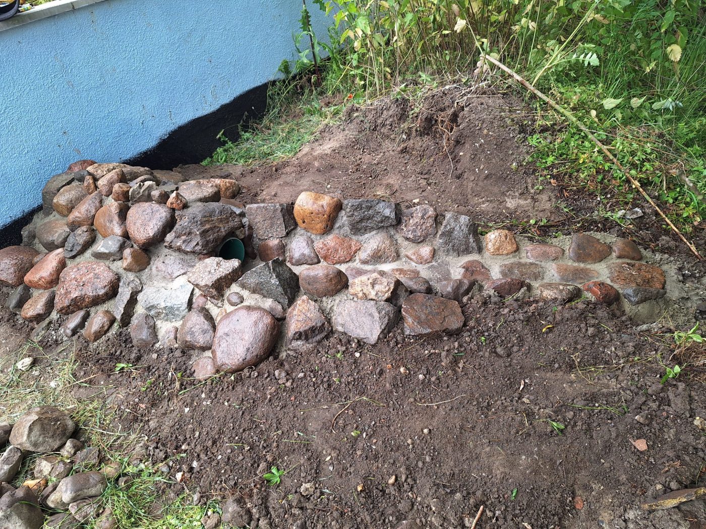 Entwässerungsrinne aus Natursteinen entlang der Hauswand
